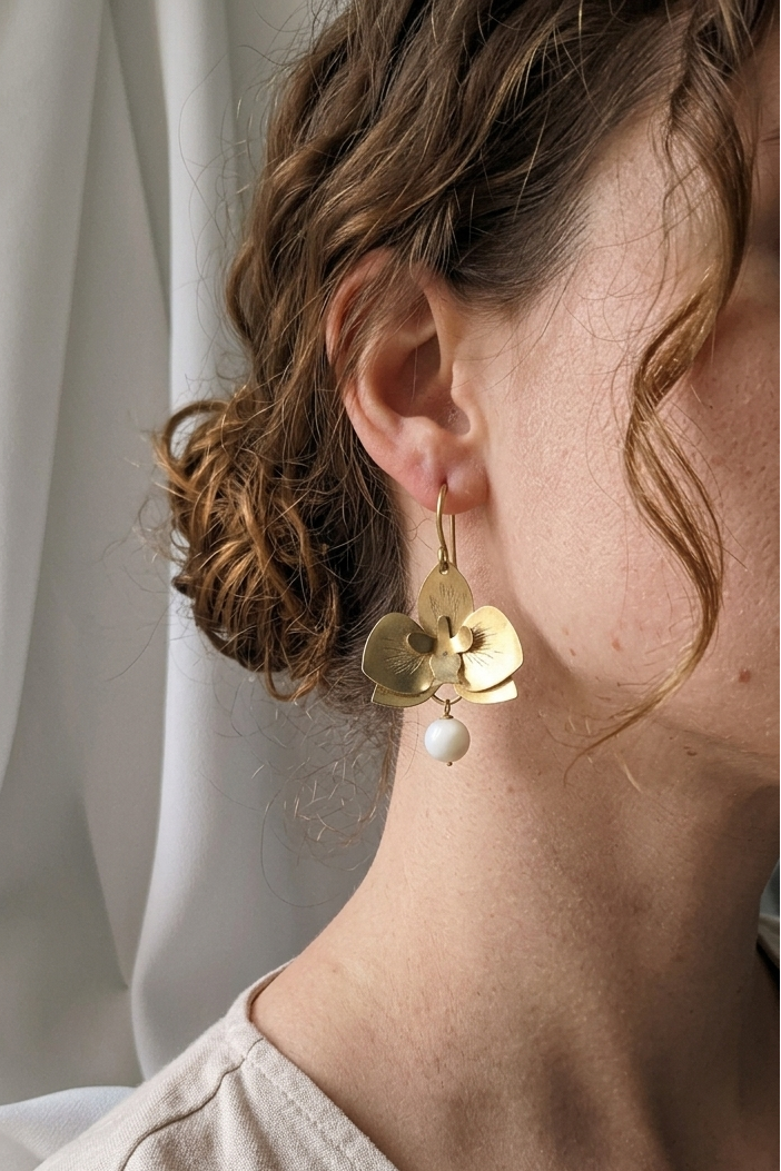 orecchini in ottone a forma di orchidea con madreperla indossati